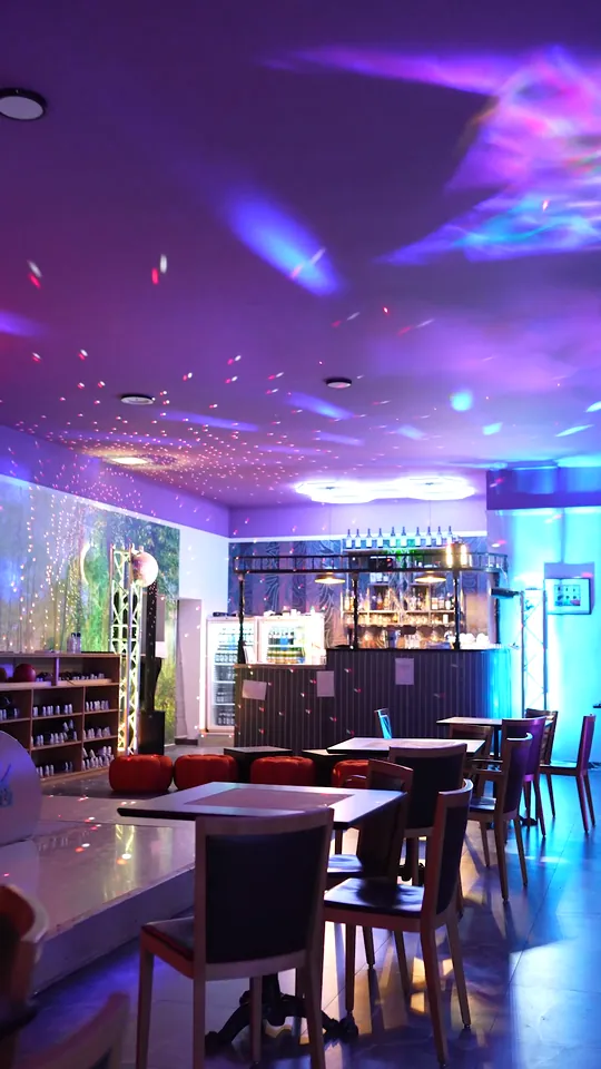 Sala Americanos Bowling noaptea, cu tavan cu stele, mese și barul luminat în fund