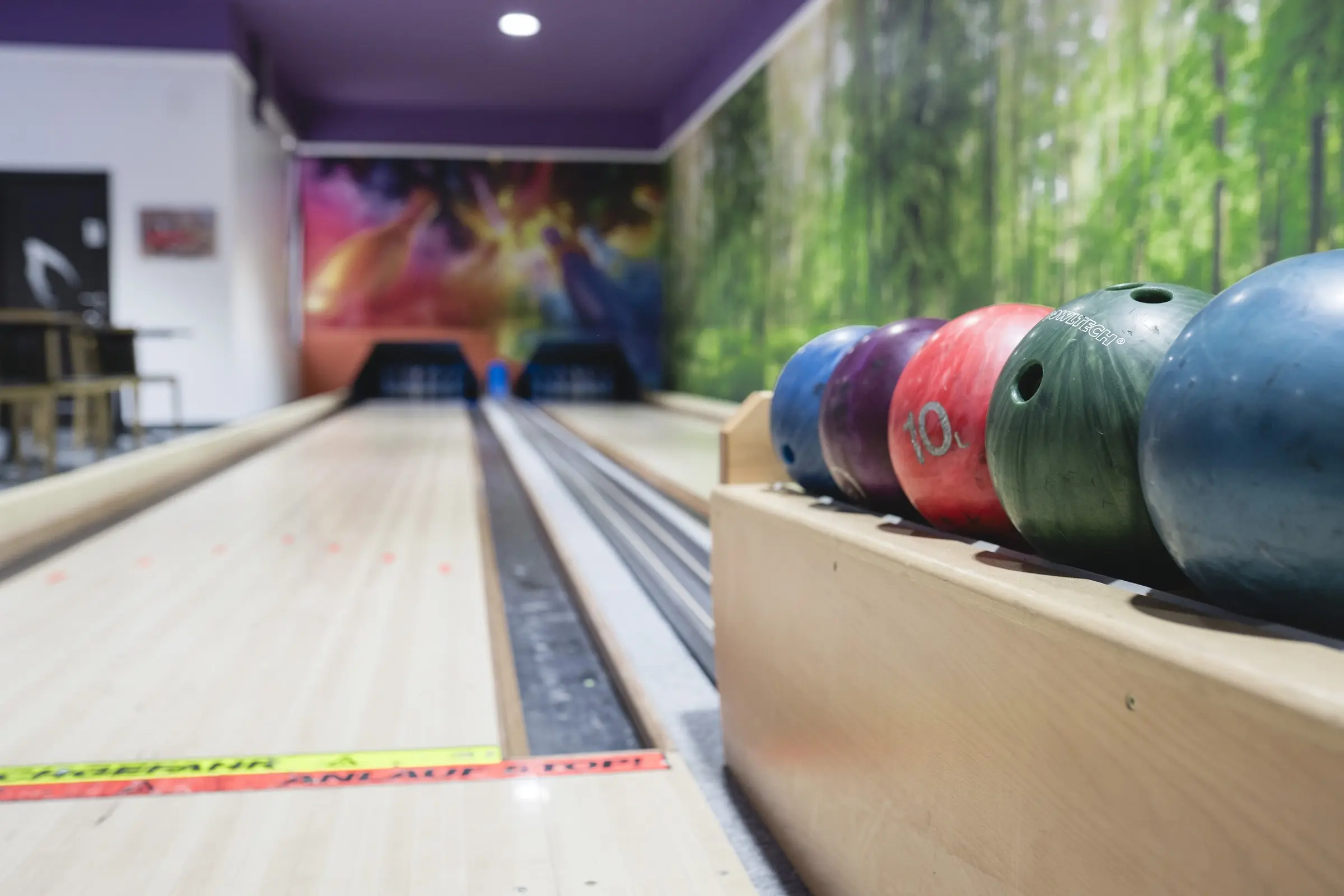 Bile de bowling colorate pe rack, lângă pistă
