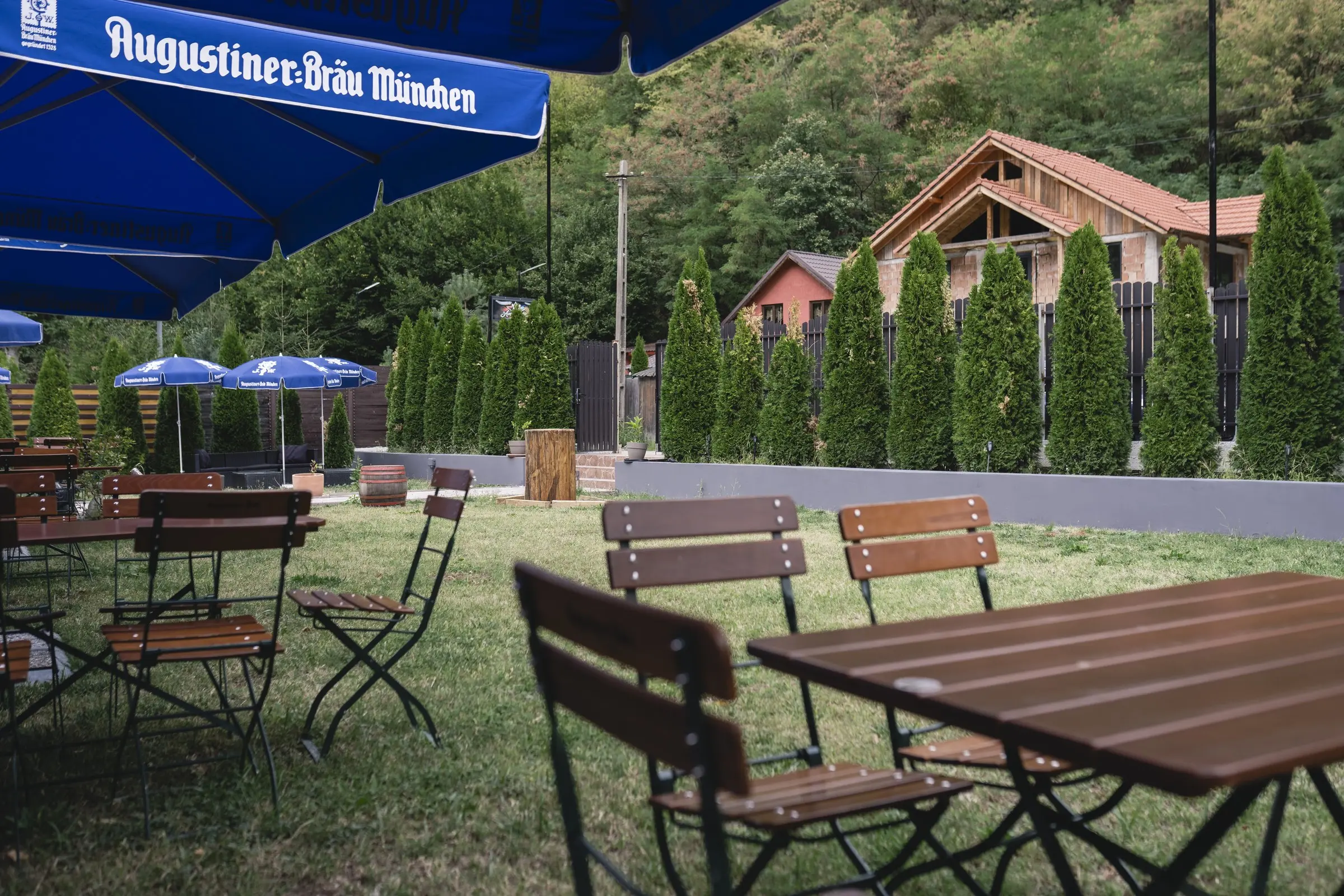 Mese de lemn pe terasa Americanos, sub o umbrelă Augustiner